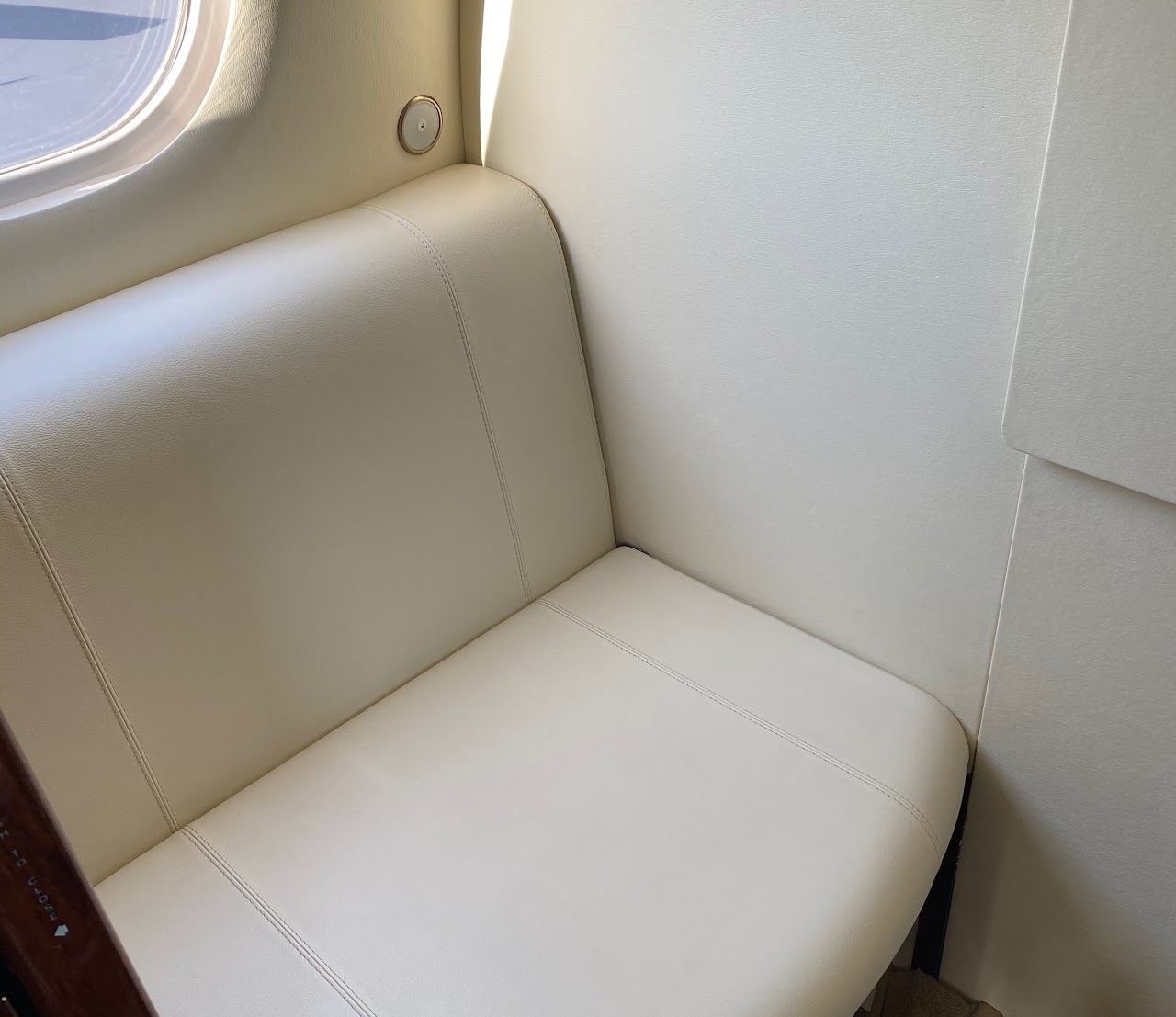 Aft cabin seat in cream leather beside a window