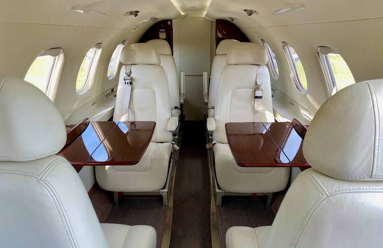 Cabin interior with four club seats and deployed wood tables